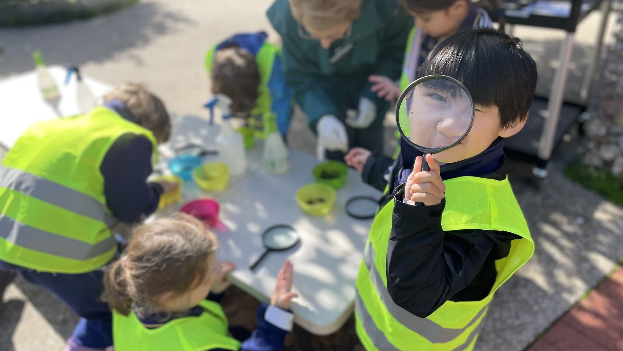 ELC student with magnifying glass alongside other students at Adelaide Botanic Garden July 26