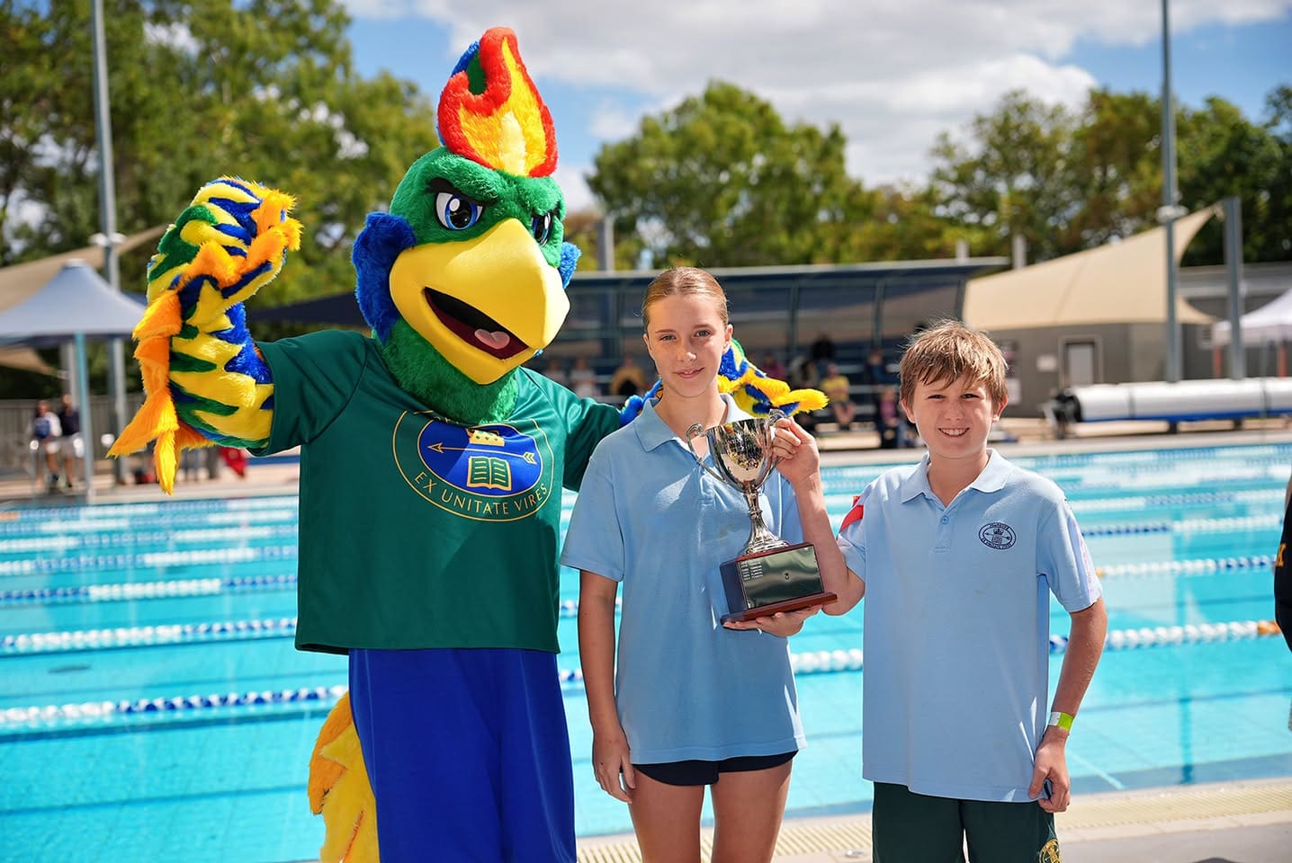 Pemboke Phoenix poses with two Junior School students with cup at Swimming Carnival
