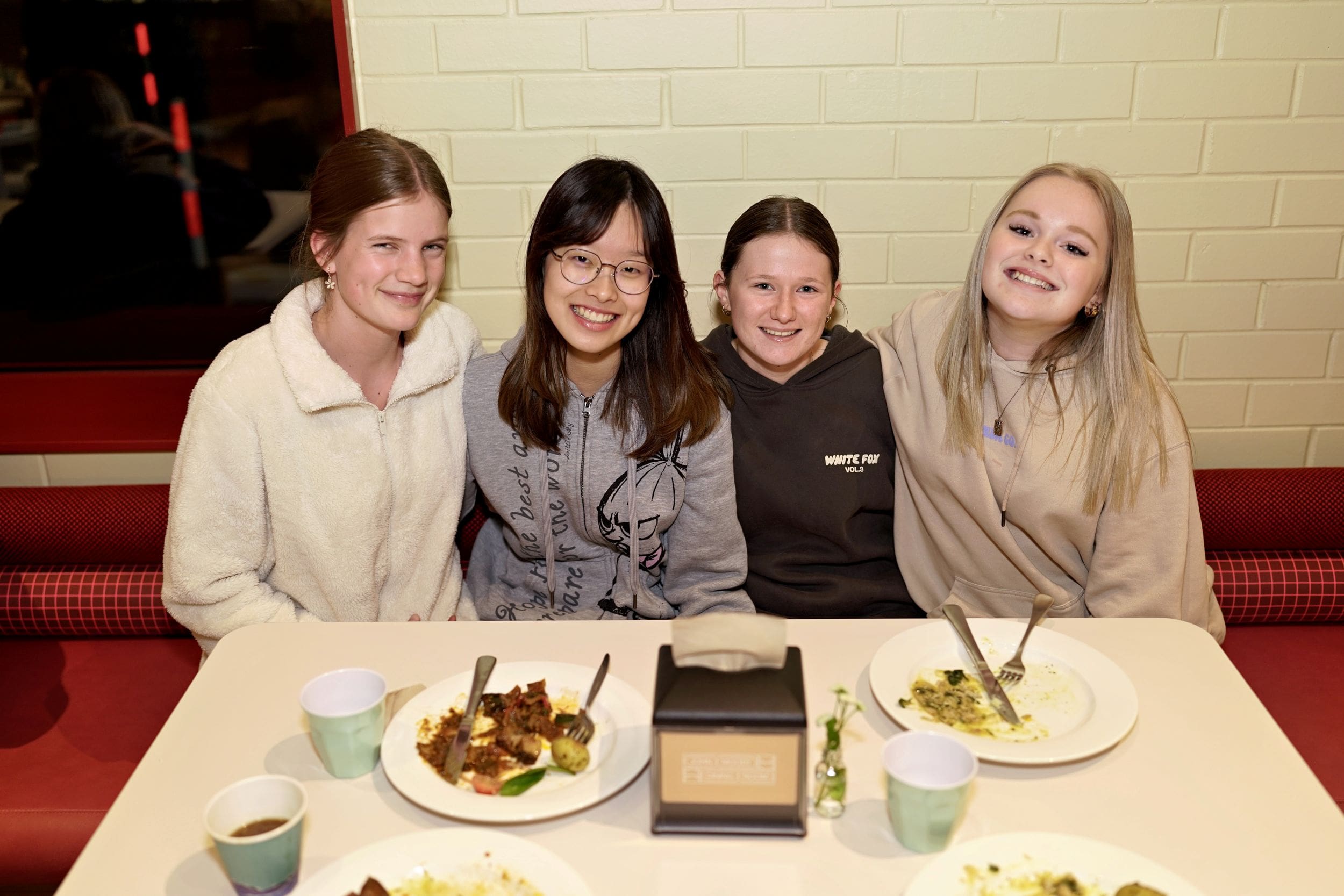 four boarding students sitting at a table during dinner service