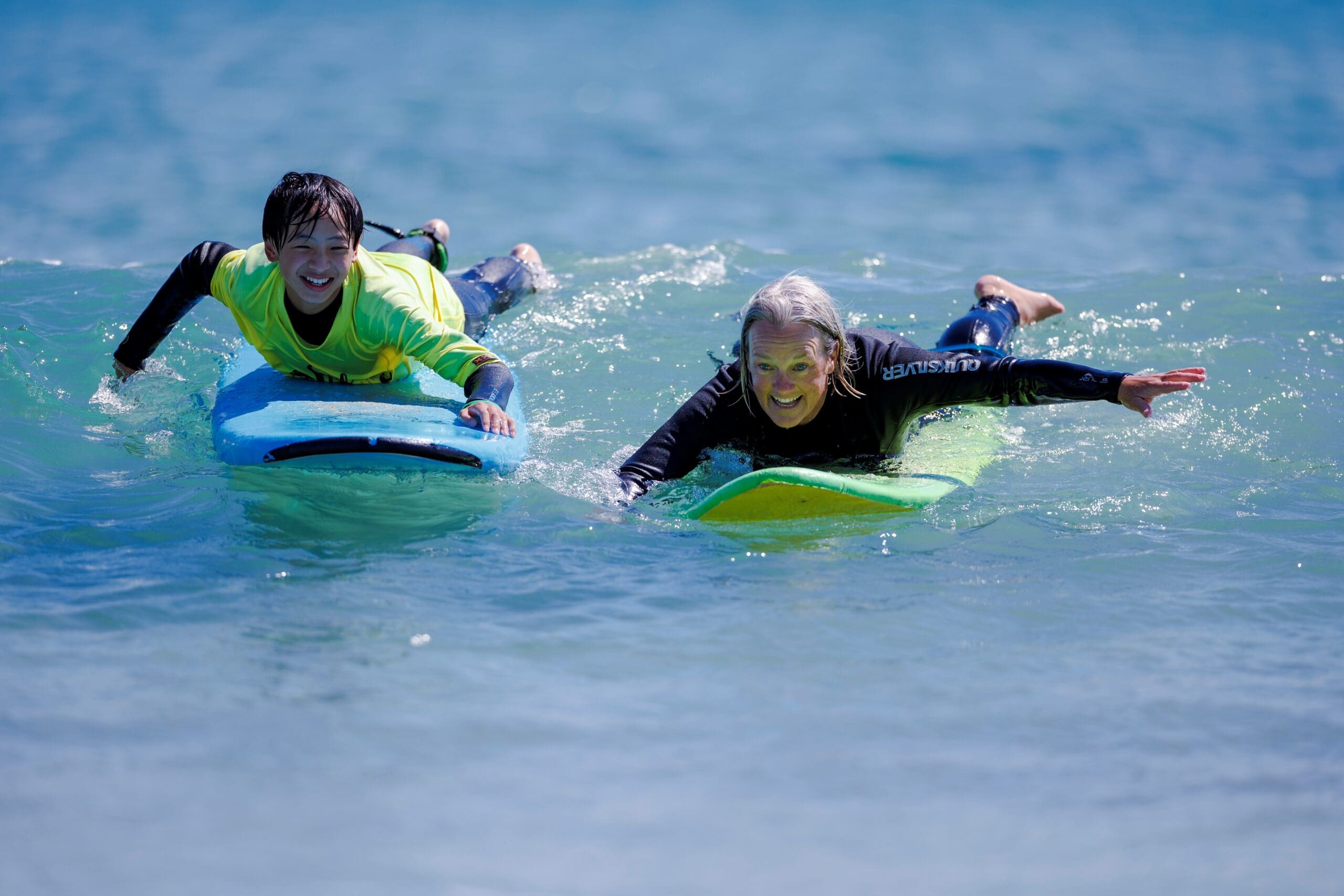 Student and teacher on surfboards on Year 7 Camp